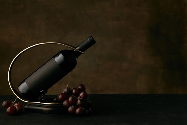 暗闇の中でワインボトルとブドウのおいしいブドウプレートの正面図