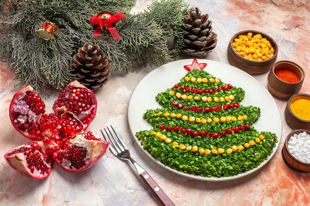 Бесплатное фото Вид спереди вкусный зеленый салат в форме новогодней елки с приправами на светлом фоне