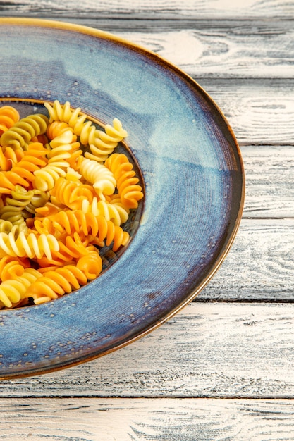 Front view tasty italian pasta unusual cooked spiral pasta on grey wooden desk cooking meal dinner pasta dish