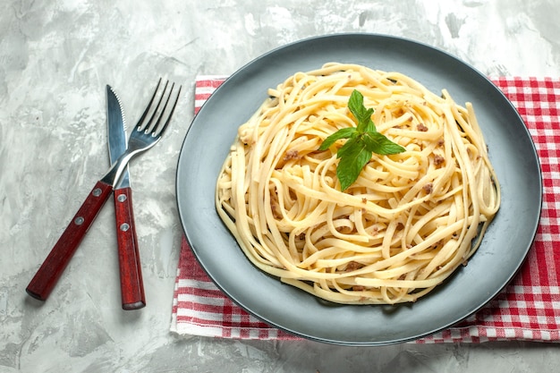 Vista frontale gustosa pasta italiana con posate su pasta bianca foto colore piatto cibo