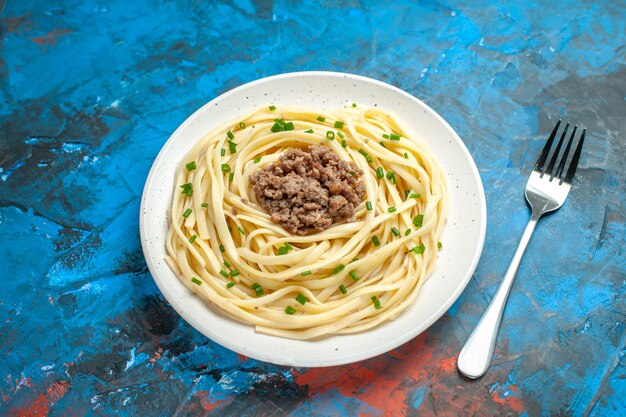 Вид спереди вкусная итальянская паста с мясным фаршем и вилкой на синем тесте, блюдо цвета еды