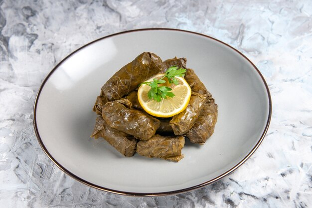 Front view of tasty leaf dolma inside plate on white surface