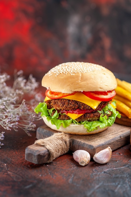 Вид спереди вкусный мясной бургер с картофелем фри на темном фоне
