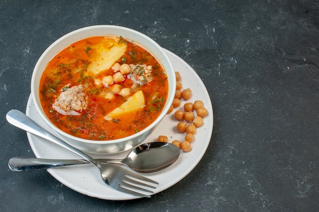 暗いテーブルの上に豆の緑とジャガイモを添えた正面図のおいしい肉スープ