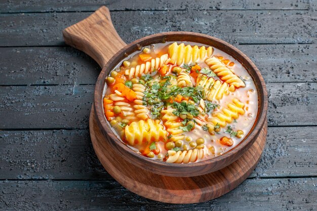 Front view tasty pasta soup from spiral italian pasta with greens on dark-blue desk color cuisine dish italian pasta soup