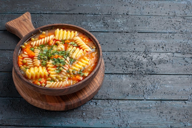 Бесплатное фото Вид спереди вкусный суп-паста из спиральной итальянской пасты с зеленью на темно-синем столе цветное блюдо итальянская паста-суп