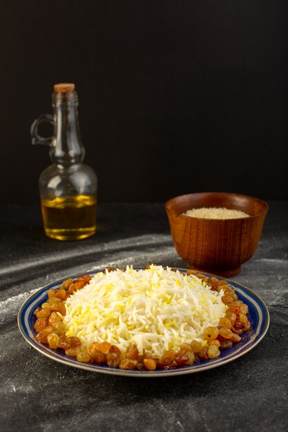 어두운 표면에 접시 안에 기름과 말린 건포도와 맛있는 필라프의 전면보기