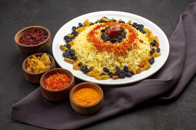 Front view tasty plov famous eastern meal consists of cooked rice and raisins on dark space