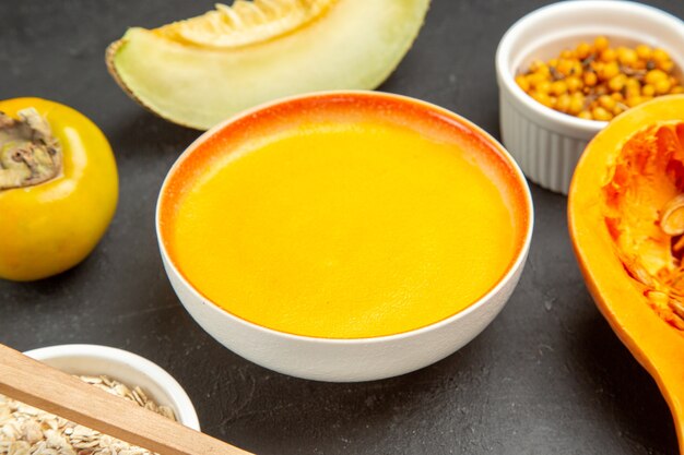 Вид спереди вкусный тыквенный суп внутри тарелки на темном столе, блюдо, цветной суп