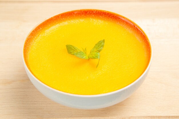 Вид спереди вкусный тыквенный суп внутри тарелки на светлом столе, блюдо, цвет супа