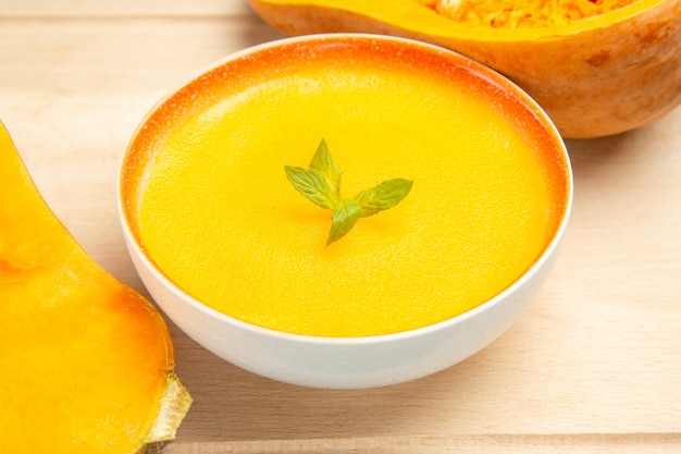 Front view tasty pumpkin soup with fresh pumpkins on light desk dish fruit soup