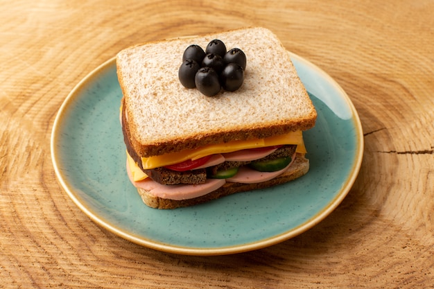 正面の明るいブループレート内のオリーブハムトマト野菜とおいしいサンドイッチ