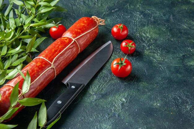 Вид спереди вкусная колбаса с красными помидорами на темной поверхности