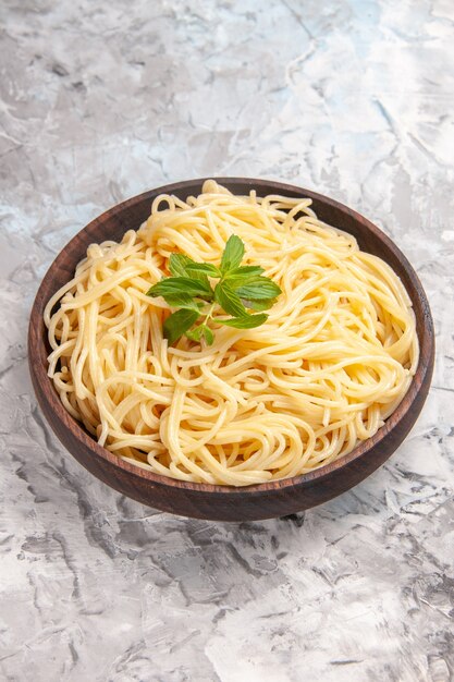 Front view tasty spaghetti with green leaf on a white table meal dish dough pasta