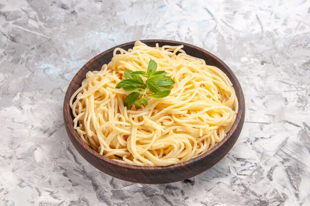 Front view tasty spaghetti with green leaf on white table meal dish dough pasta