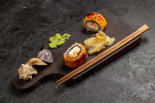 Вид спереди вкусных рыбных рулетов с суши с соусом вассаби на серой стене