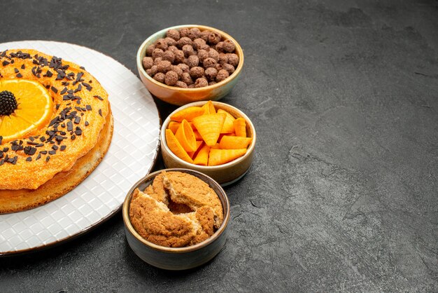 Вид спереди вкусный сладкий пирог с дольками апельсина на темном фоне сладкий пирог десертный чай бисквитный торт сахар