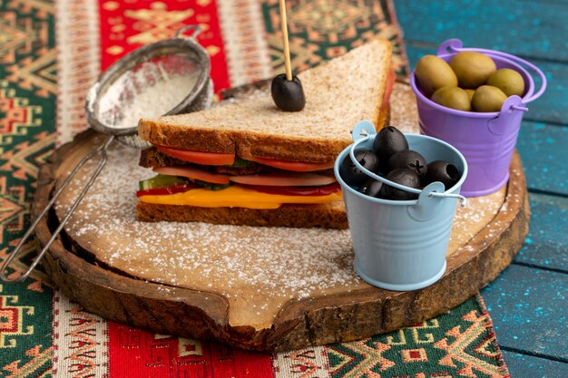 Front view tasty toast sandwich with cheese ham inside along with flour olives on blue