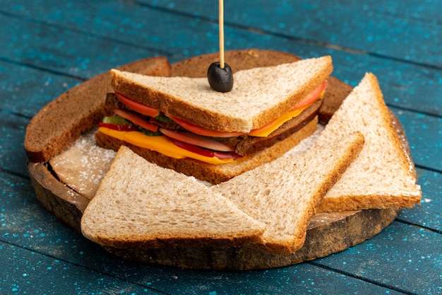 Front view tasty toast sandwich with cheese ham inside with bread loafs on blue