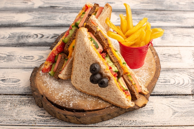 Вид спереди вкусные бутерброды с тостами с сырной ветчиной внутри с картофелем фри на дереве