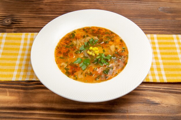 Front view tasty vegetable soup inside plate on brown wooden desk