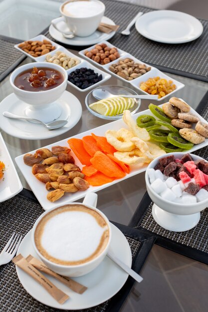 A front view tea table with jam coffee marmalade nuts sweets dried fruits and candies in the restaurant during daytime tea table sweet outside