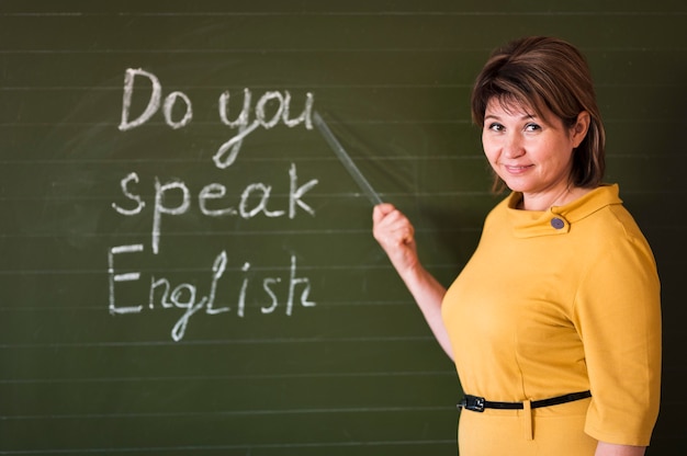 Front view teacher writing at chalkboard