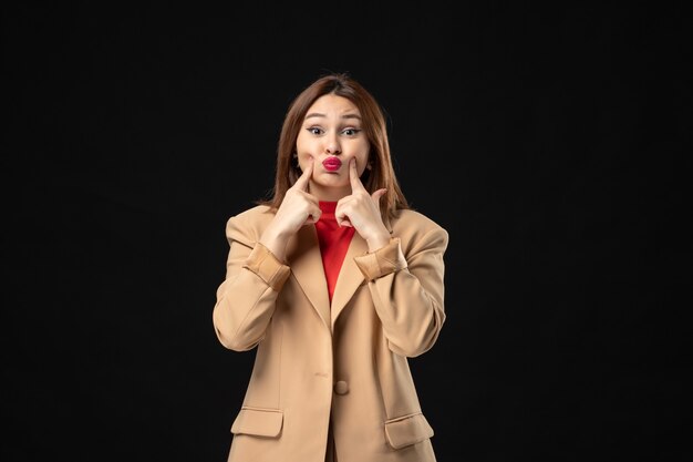 Front view of tense and emotional young lady in a light brown suit on dark