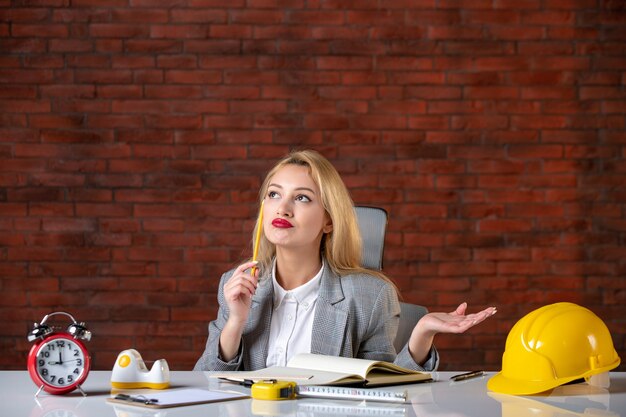 Front view thinking female engineer sitting at the office