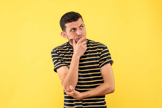 Вид спереди мышления красивый мужчина в черно-белой полосатой футболке на желтом изолированном фоне
