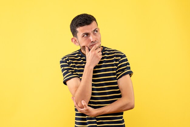 Front view thinking handsome man in black and white striped t-shirt yellow isolated background