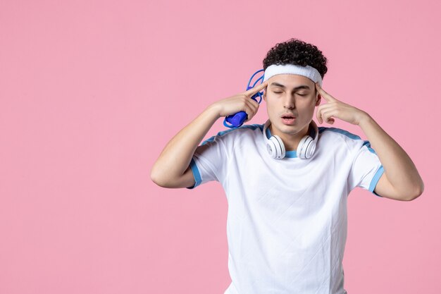 Front view thinking young male in sport clothes with skipping rope