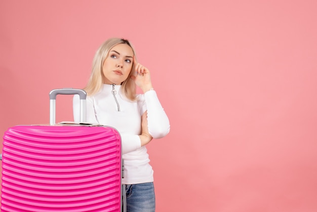 Front view thoughtful beautiful woman with pink suitcase