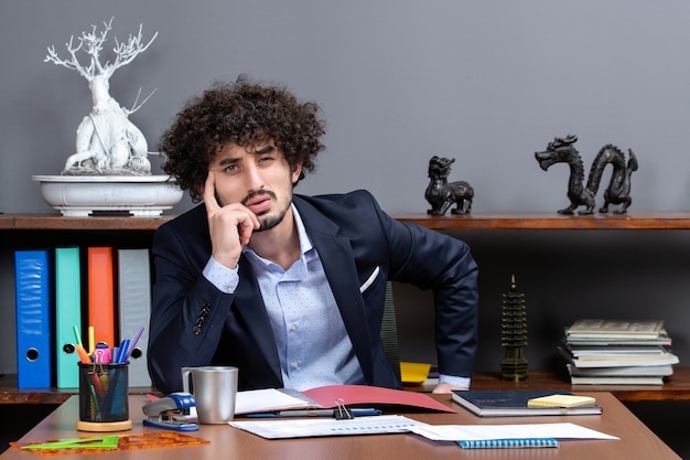 Free photo front view of thoughtful businessman sitting at his desk in office