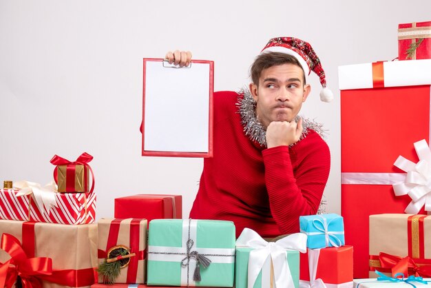 Front view thoughtful young man sitting around xmas gifts