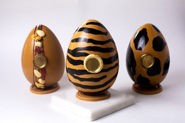 Front view three chocolate eggs in gold and black in gold tiger and leopard colors on stand