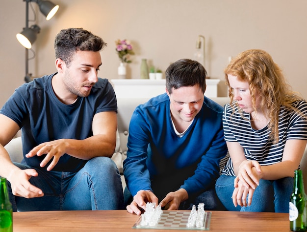 Front view of three friends at home playing chess