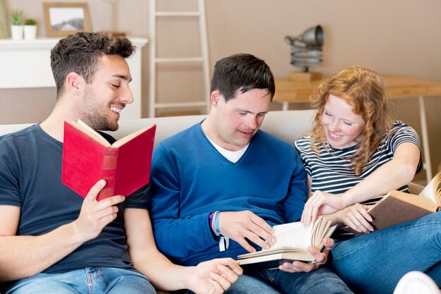 Front view of three friends reading on sofa