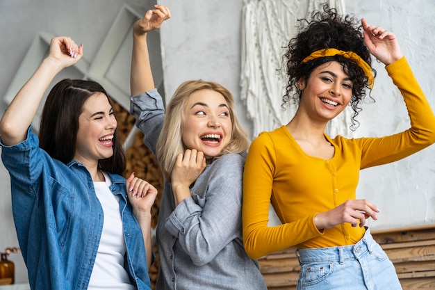 Front view of three happy women smiling and dancing