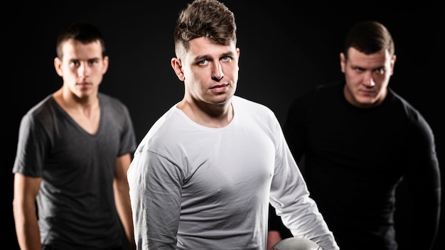 Front view of three male rugby players posing with ball