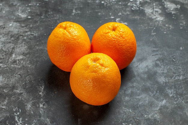 Front view of three natural organic fresh oranges on dark background