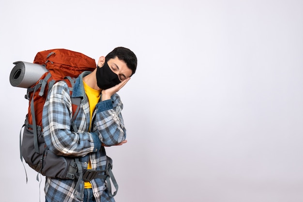 Viaggiatore maschio stanco vista frontale con zaino e maschera per dormire