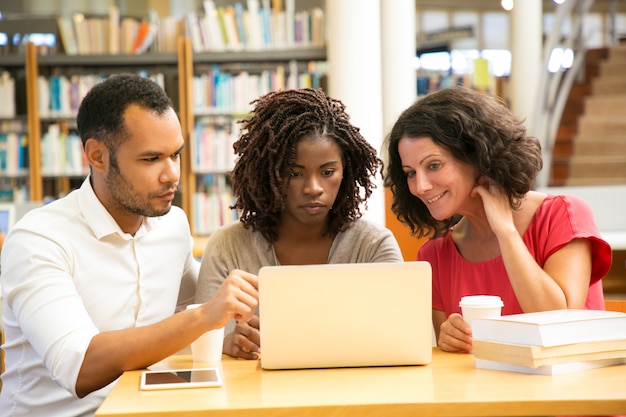 Front view of tired mature students looking at laptop