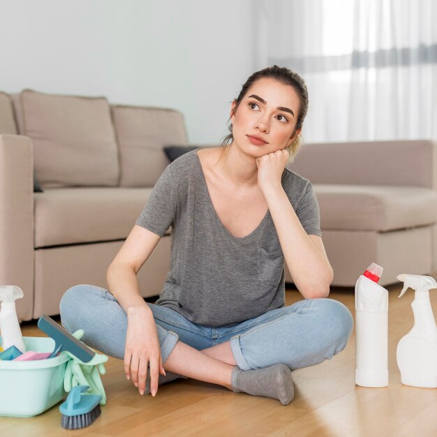 Front view of tired woman with cleaning supplies