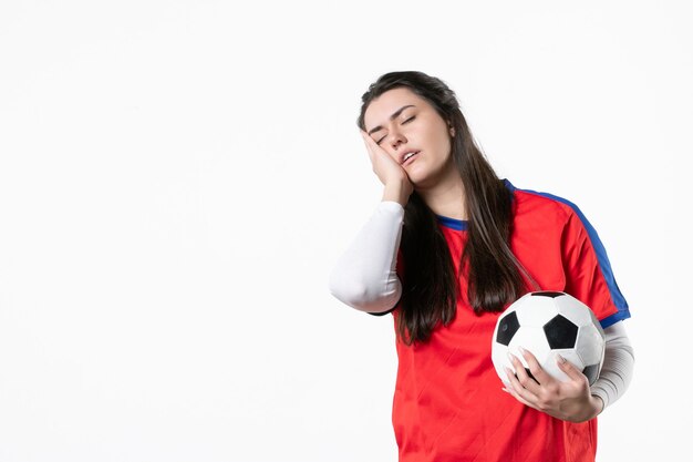 Вид спереди усталая молодая женщина в спортивной одежде с футбольным мячом