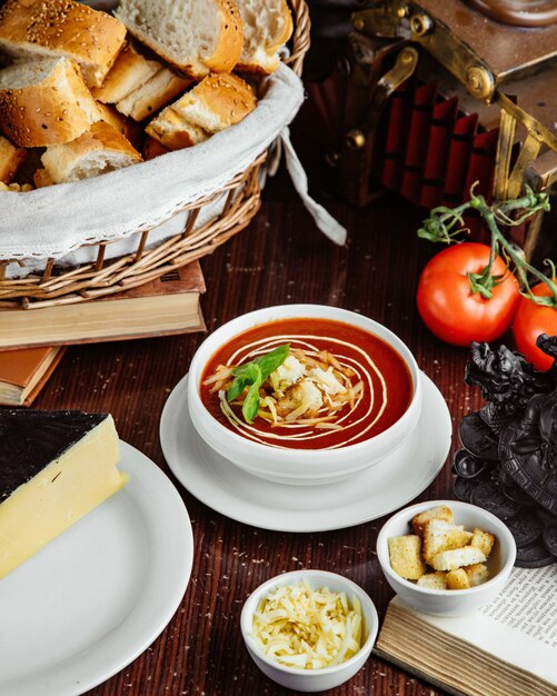 Вид спереди томатный суп с крекерами и сыром помидоры и хлеб на столе