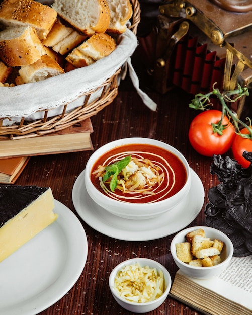 テーブルの上のクラッカーとチーズトマトとパンの正面トマトスープ