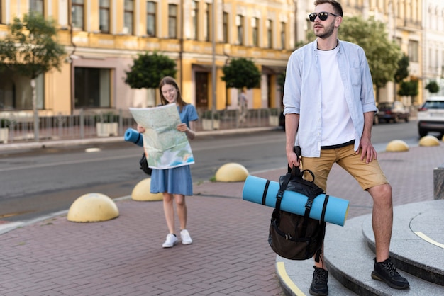 Вид спереди туристической пары, держащей карту и рюкзак