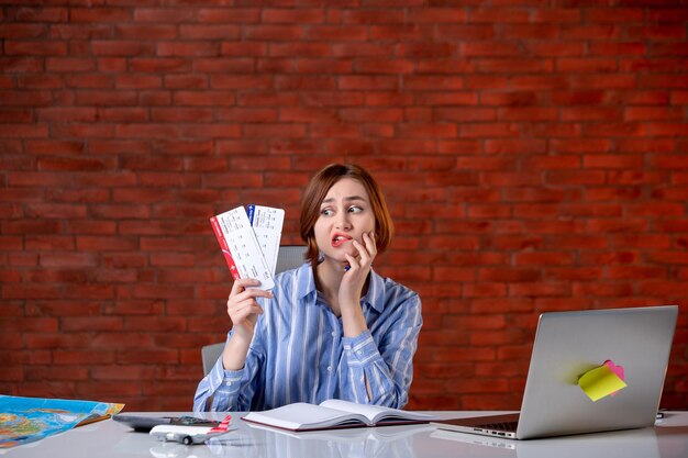 Front view travel agent sitting behind her working place with plane tickets agency service global operator manager assistant map