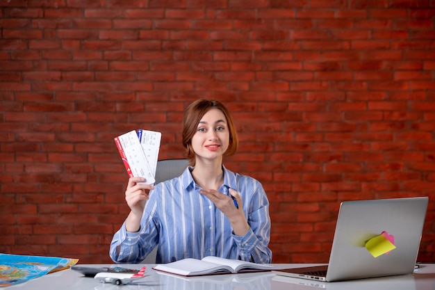 Front view travel agent sitting behind her working place with plane tickets agency service global operator manager world map